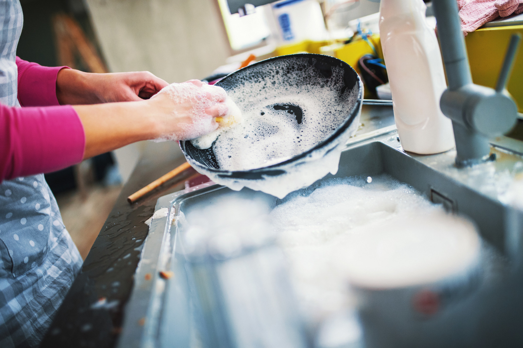 A person washes dishes in the sink