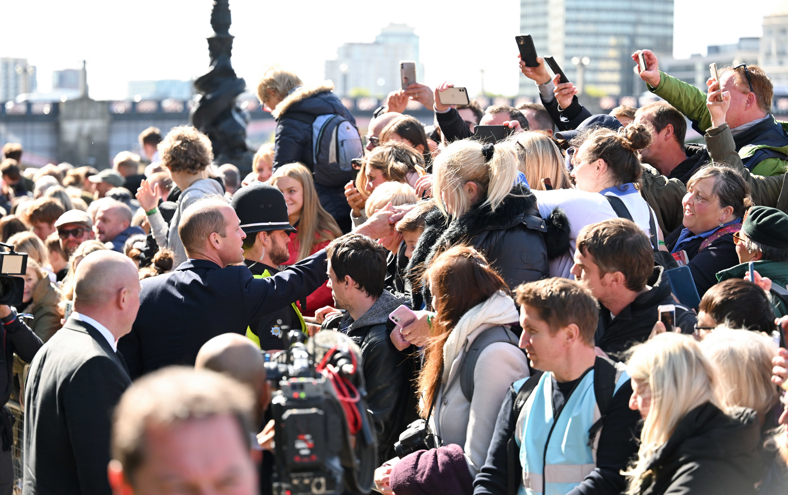 People take photos of Prince William greeting fans