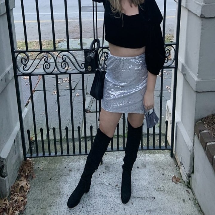reviewer wearing the boots with a sequin skirt