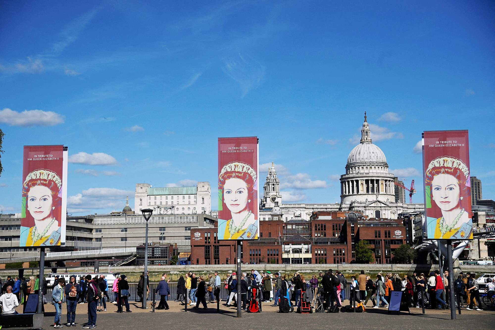 Signs with a photo of the Queen and &quot;In tribute to HM Queen Elizabeth II&quot; text above the crowd