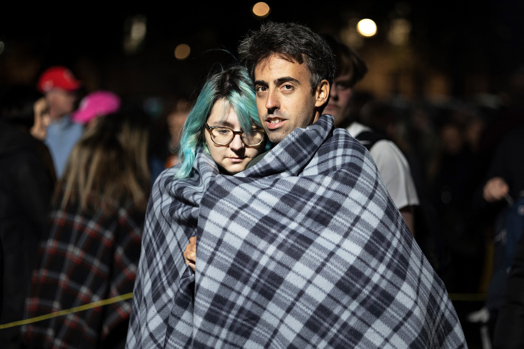 Two people standing share a blanket