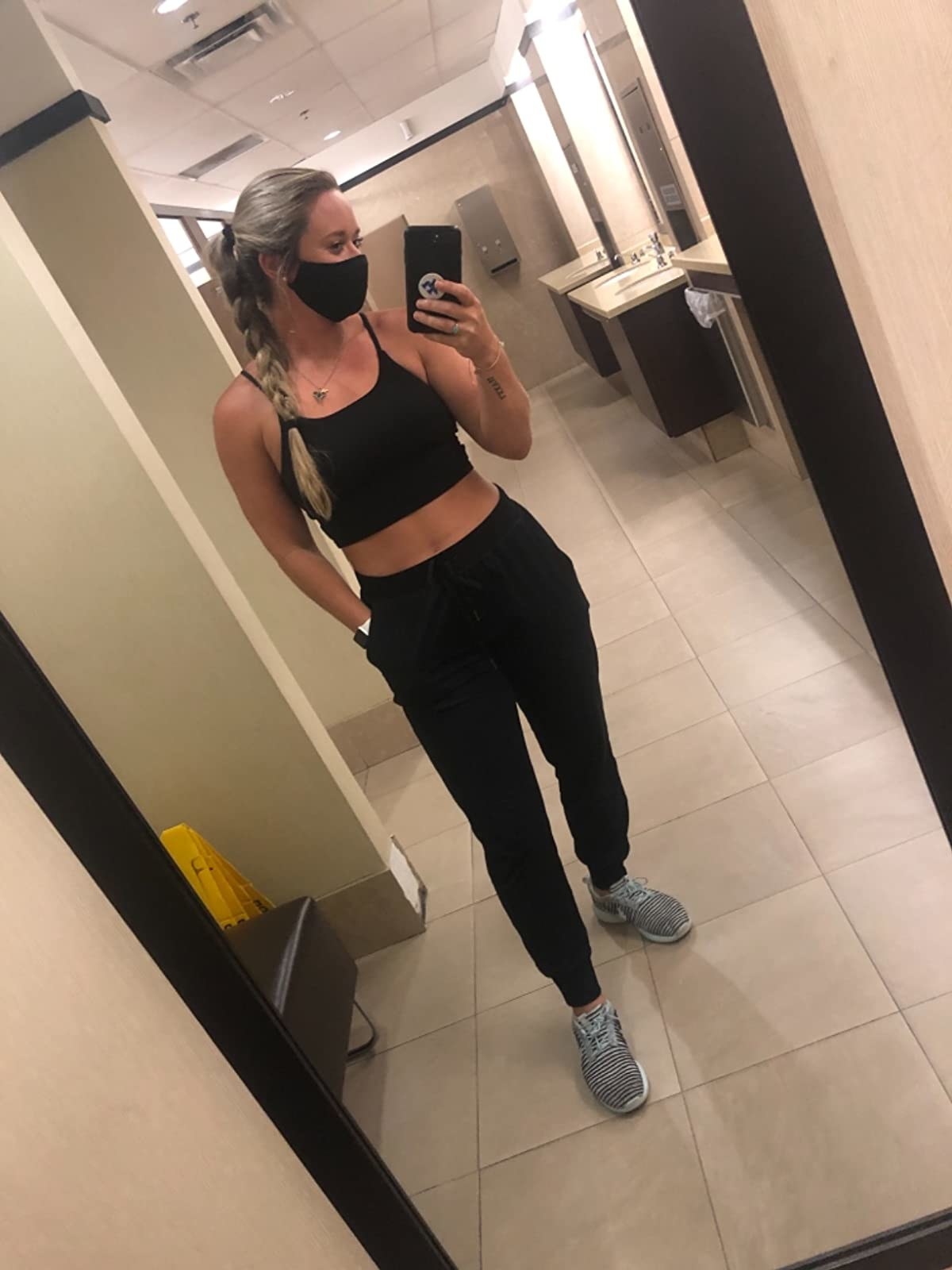 Reviewer wearing black joggers, black sports bra and sneakers
