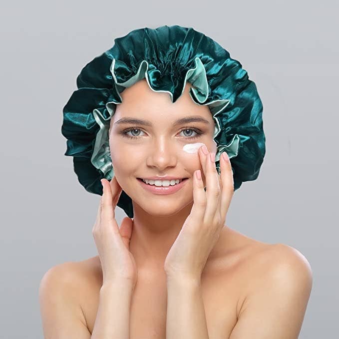 Model wearing the teal bonnet and rubbing face wash on