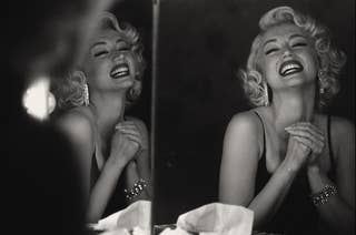 A woman smiling in the mirror and her reflection