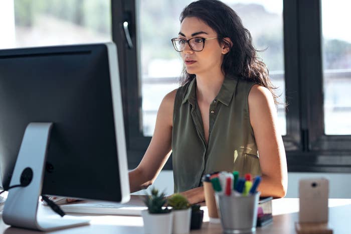 A woman works on her computer in an office setting