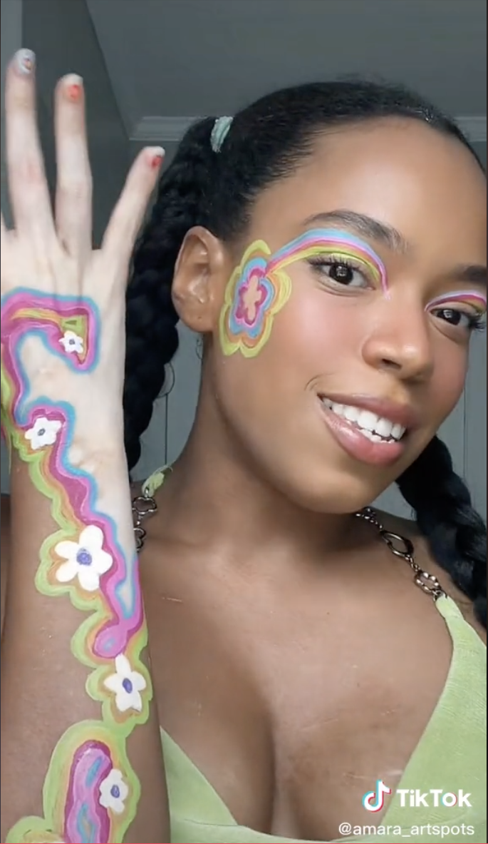Flowers and lines of several different colors run up her arm and around her vitiligo spots