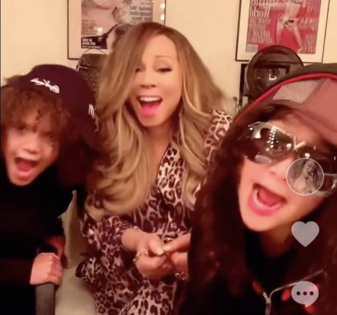 Mariah looks shocked with her two children who are wearing black hats and hoodies