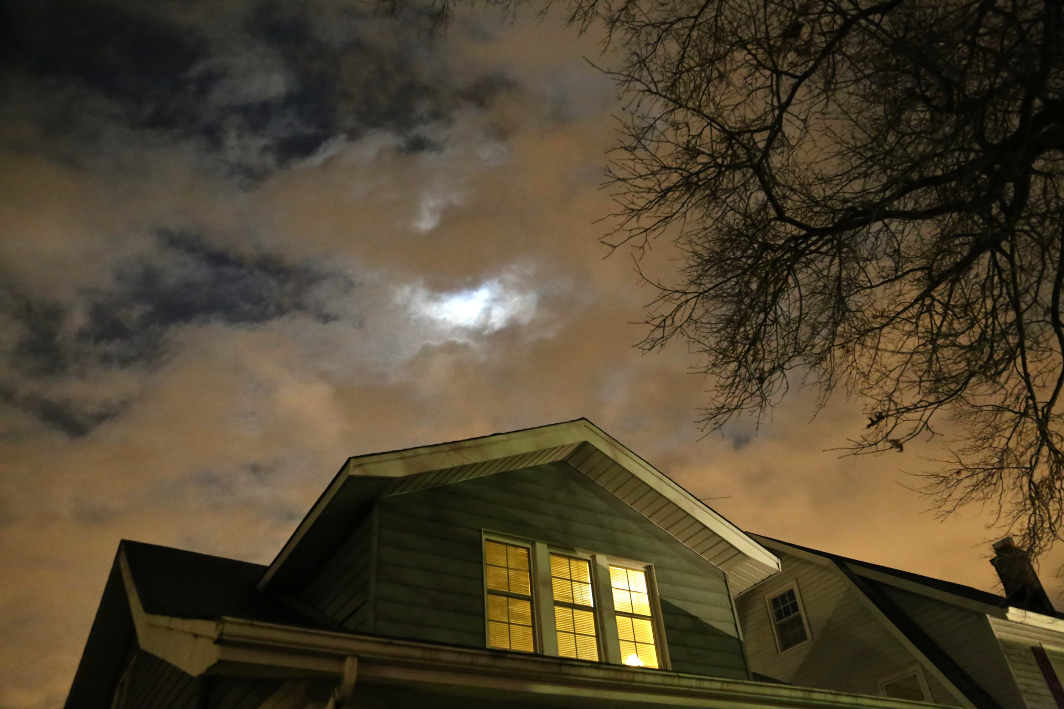 the top of a house with a spooky, cloudy night sky