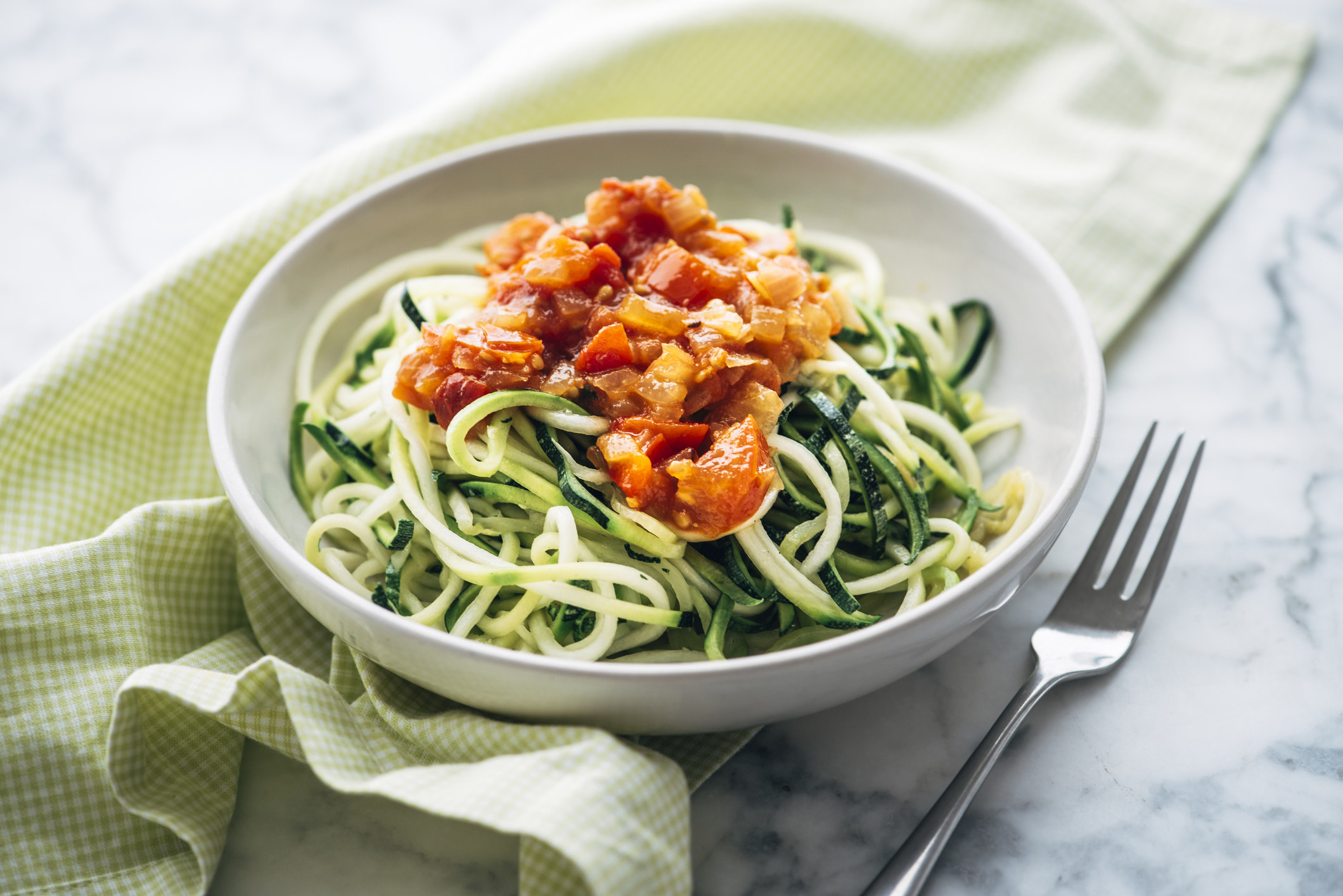 a bowl of zucchini pasta topped with a sauce