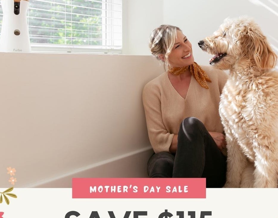 a person and a dog sitting beside a window and furbo device