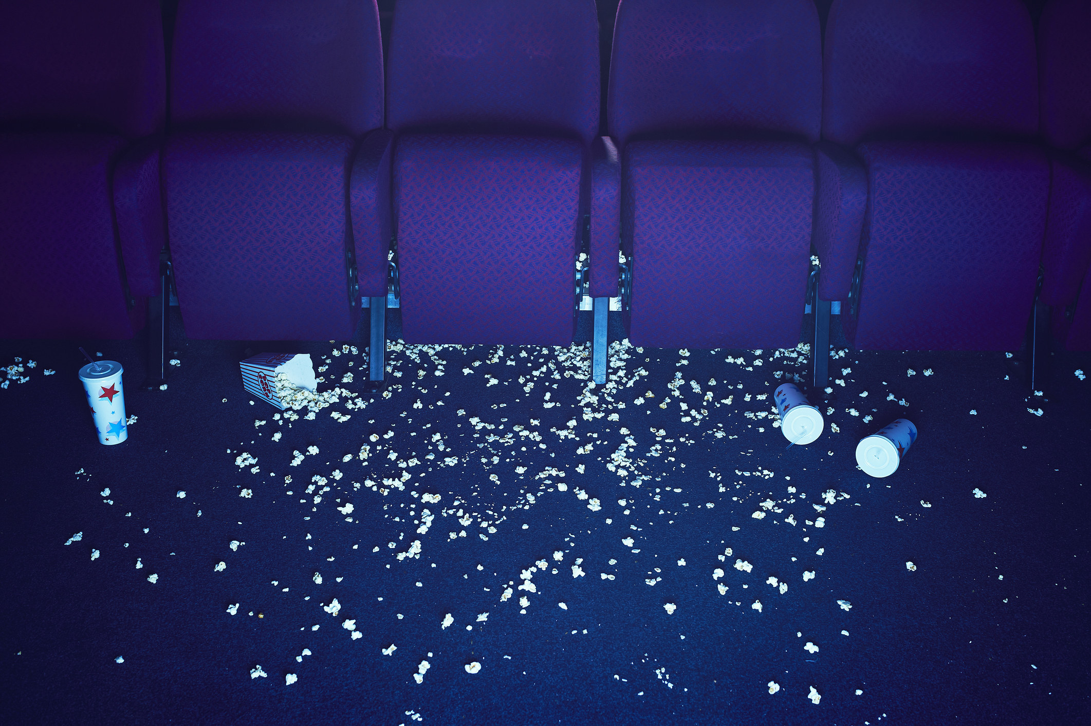 empty movie theatre with popcorn and cups strewn all over the ground