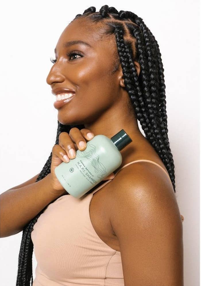 A person with braids holding a bottle shampoo