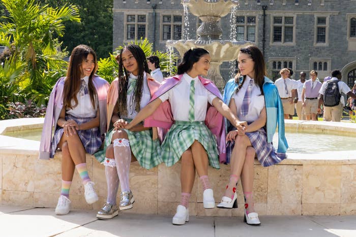 four teenage girls sitting on a fountain outside of school