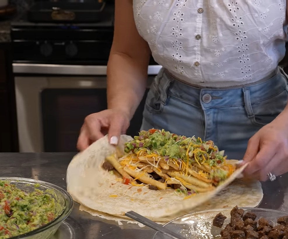 wrapping a burrito with fries, guacamole, cheese, and meat