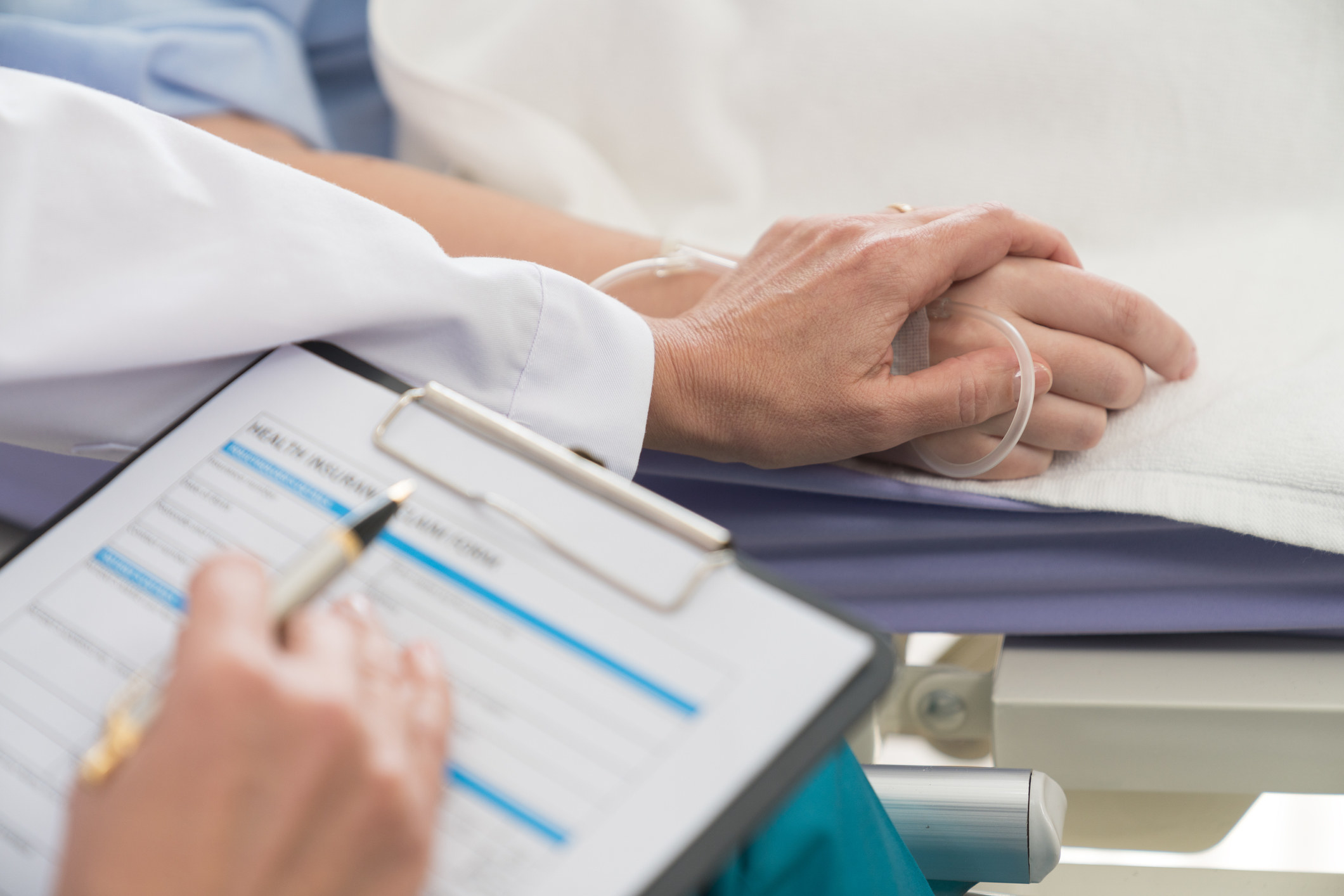 a medical worker filling out a form for a patient in a hospital bed