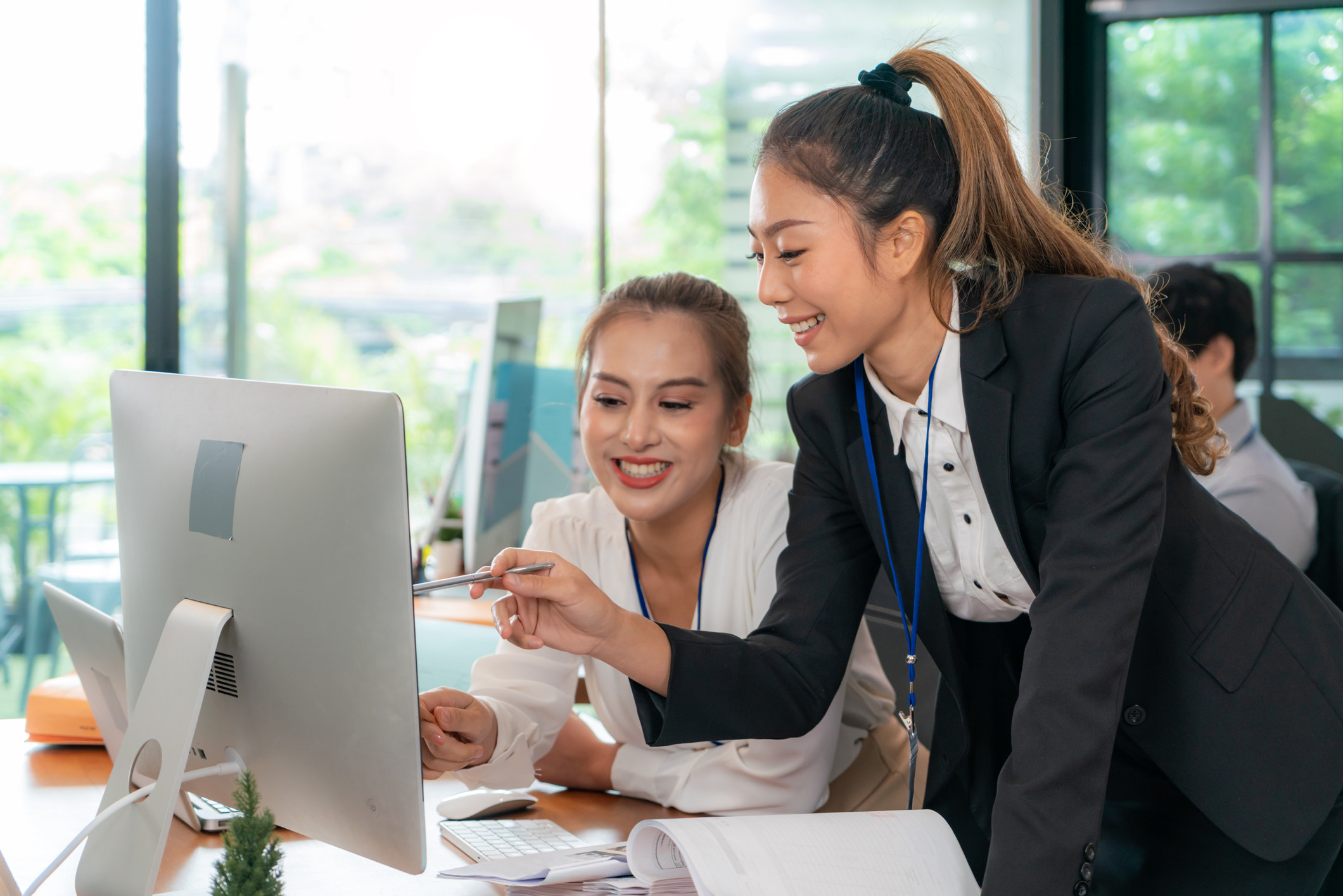 two women looking at a computer in an office and smiling