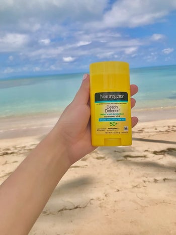 reviewer holding the sunblock stick on the beach