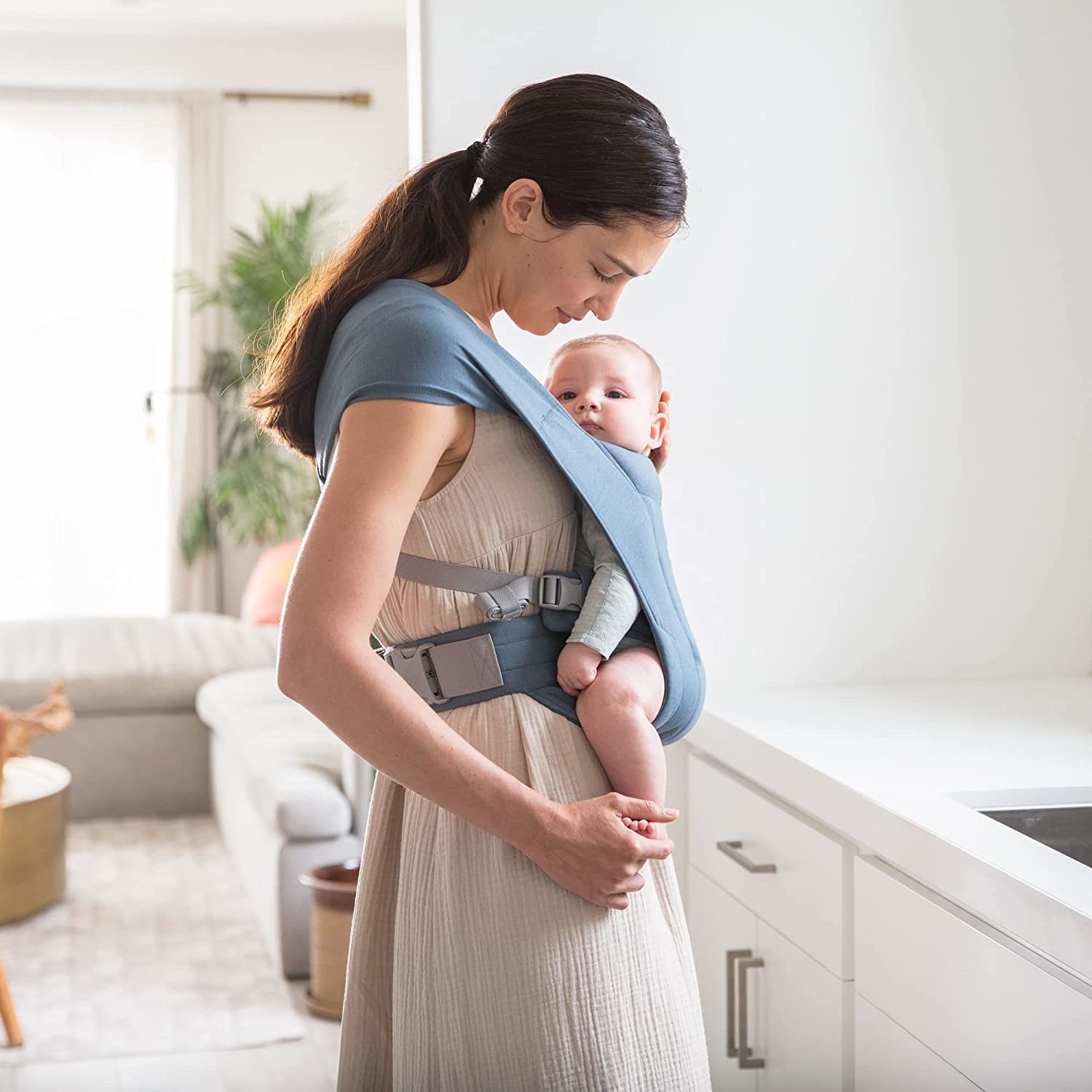 a person carrying a baby in a body sling