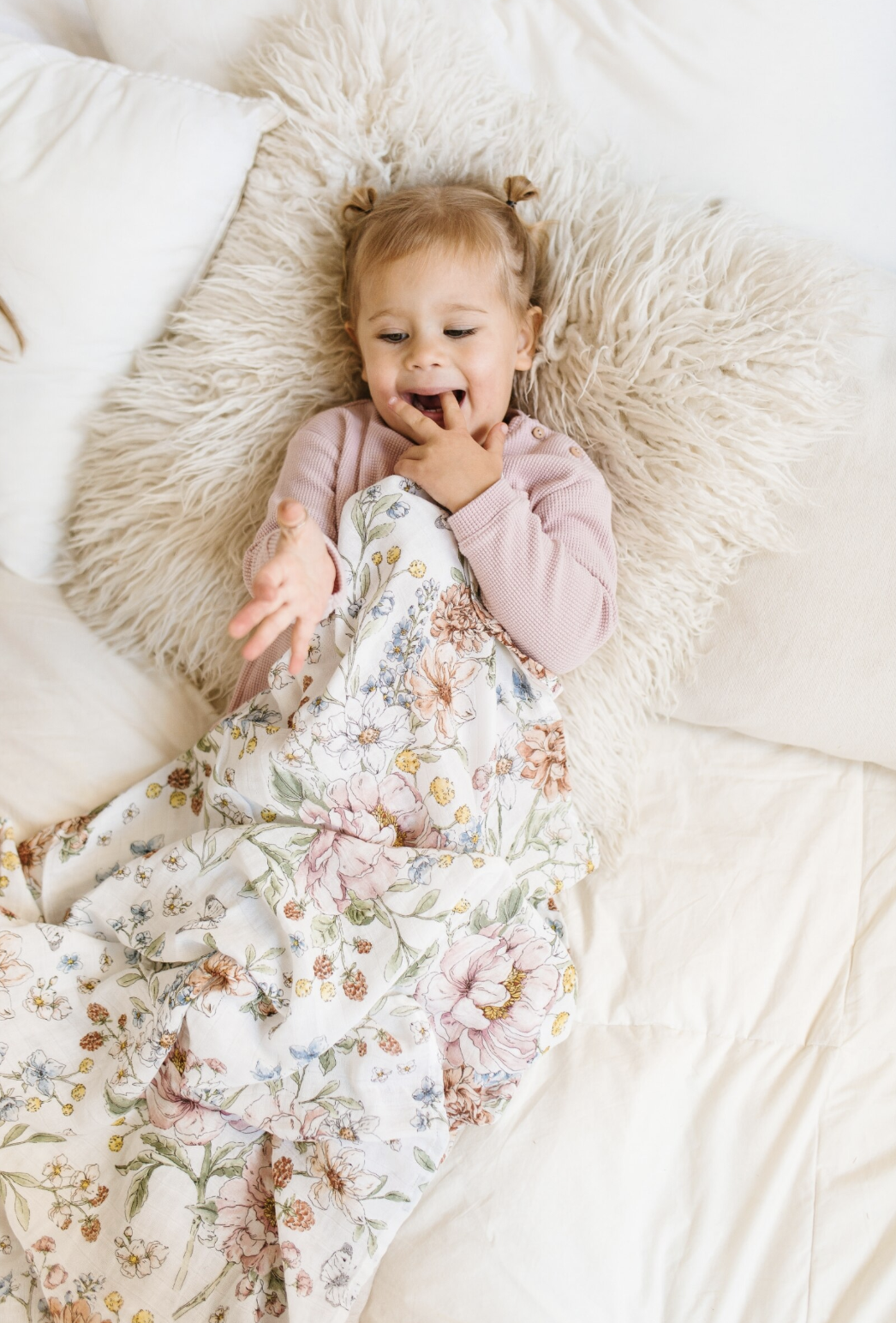 a baby in a bed holding on to a floral blanket