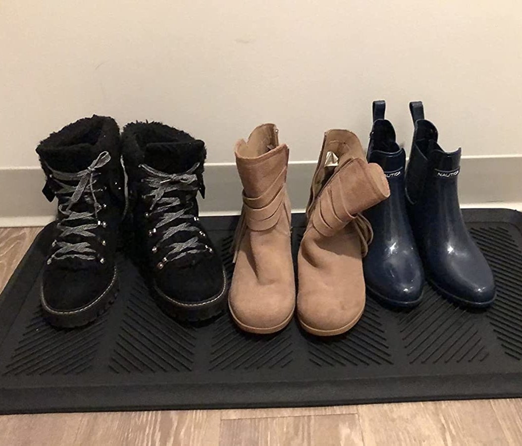 several pairs of boots sitting on a black rubber boot tray