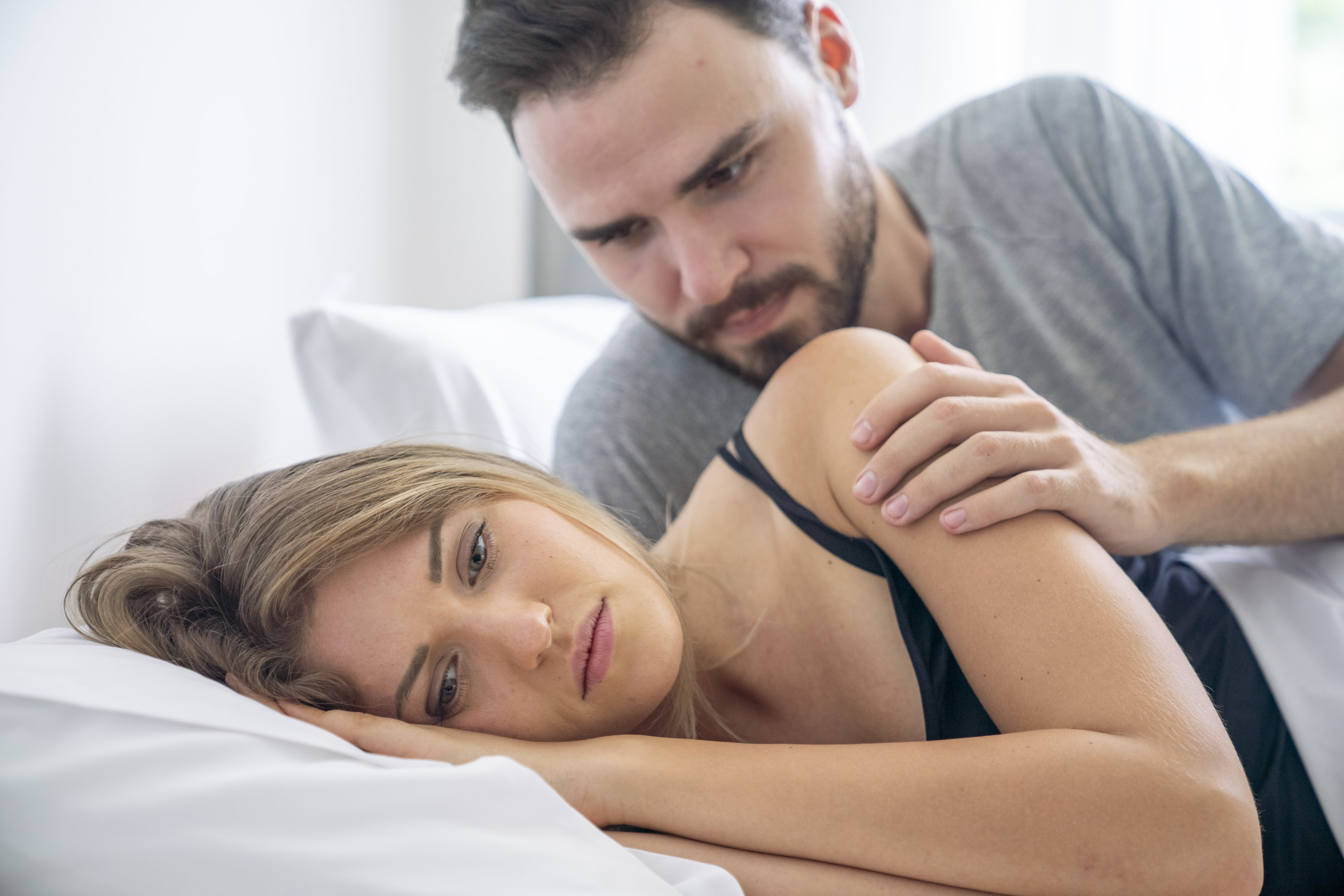 man trying to look over a woman&#x27;s shoulder in bed