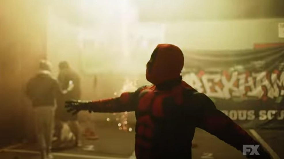 A fan of Wrexham dressed as Deadpool celebrating in front of fireworks