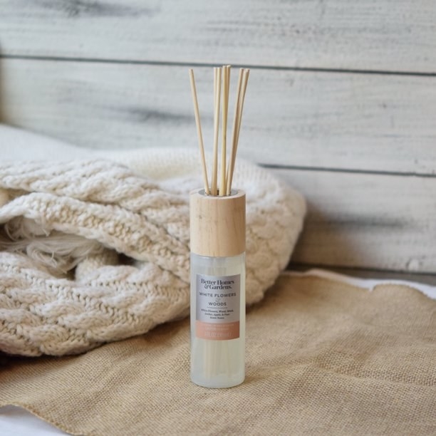 A reed diffuser with peach labels in a beige room