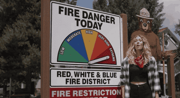 A woman pointing to a chart which displays the day&#x27;s fire danger level