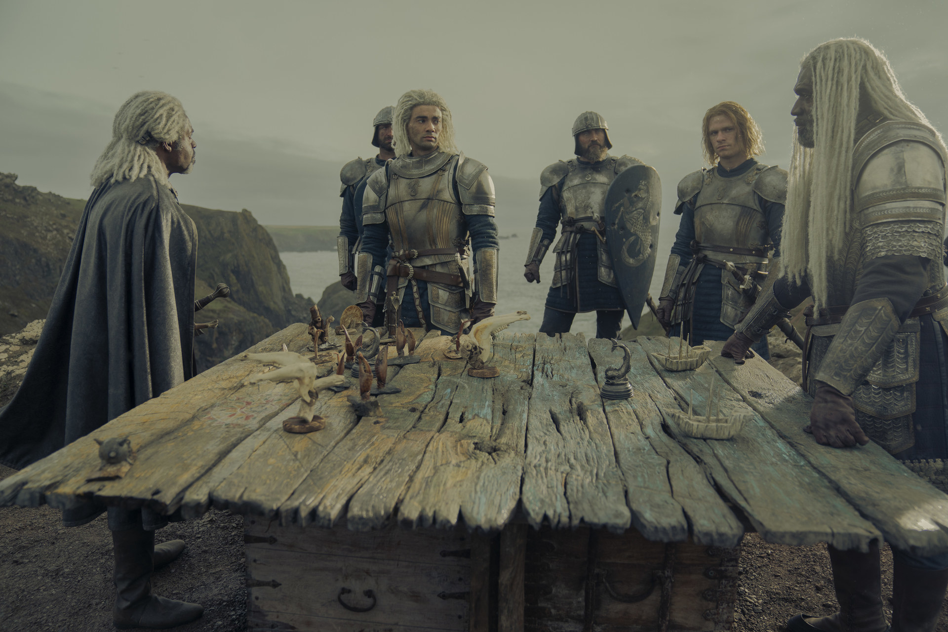 Vaemond, Corls, Laenor and Joffrey Lonmouth stand around a table talking.