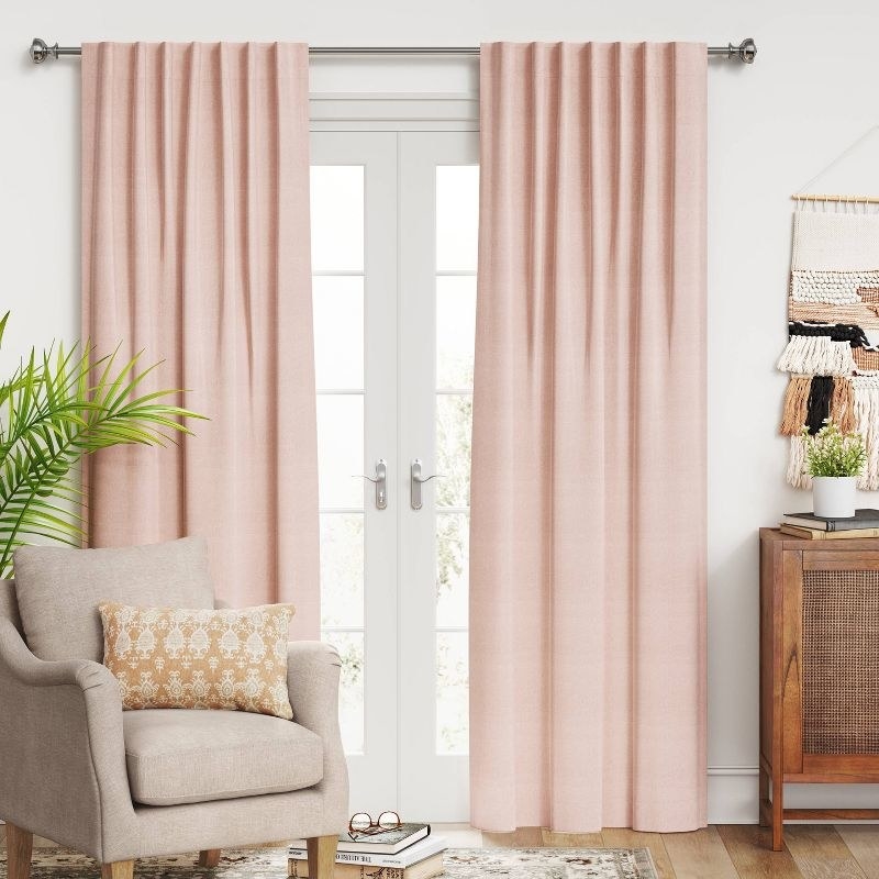a set of blush colored blackout curtains in a living room