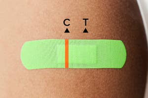 肩膀上一条鲜绿色的绷带。创可贴上有一条橙色的线，就好像创可贴是一种Covid-19测试。C代表控制，T代表测试。单线表示测试结果为阴性。