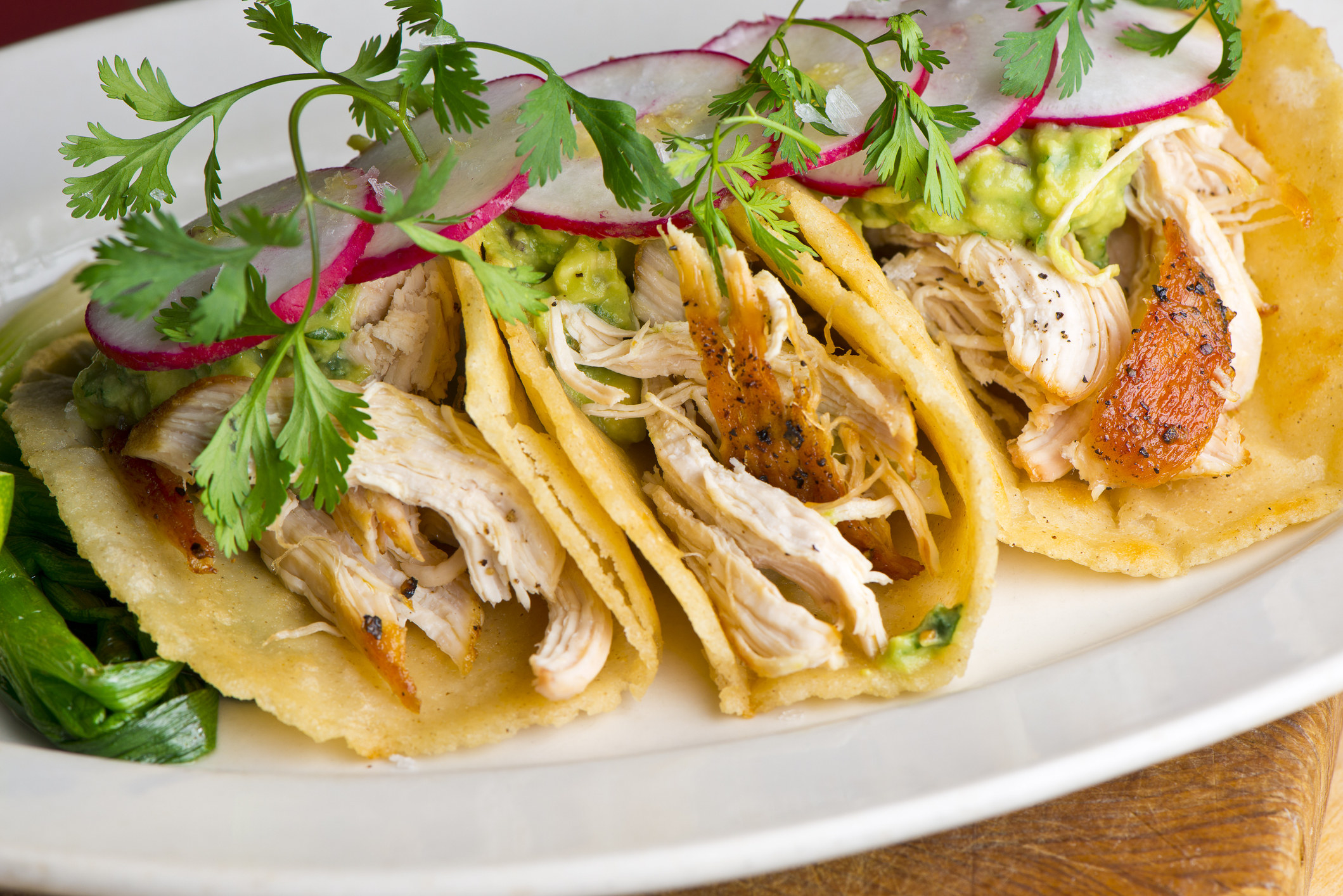 Three chicken tacos on a plate.