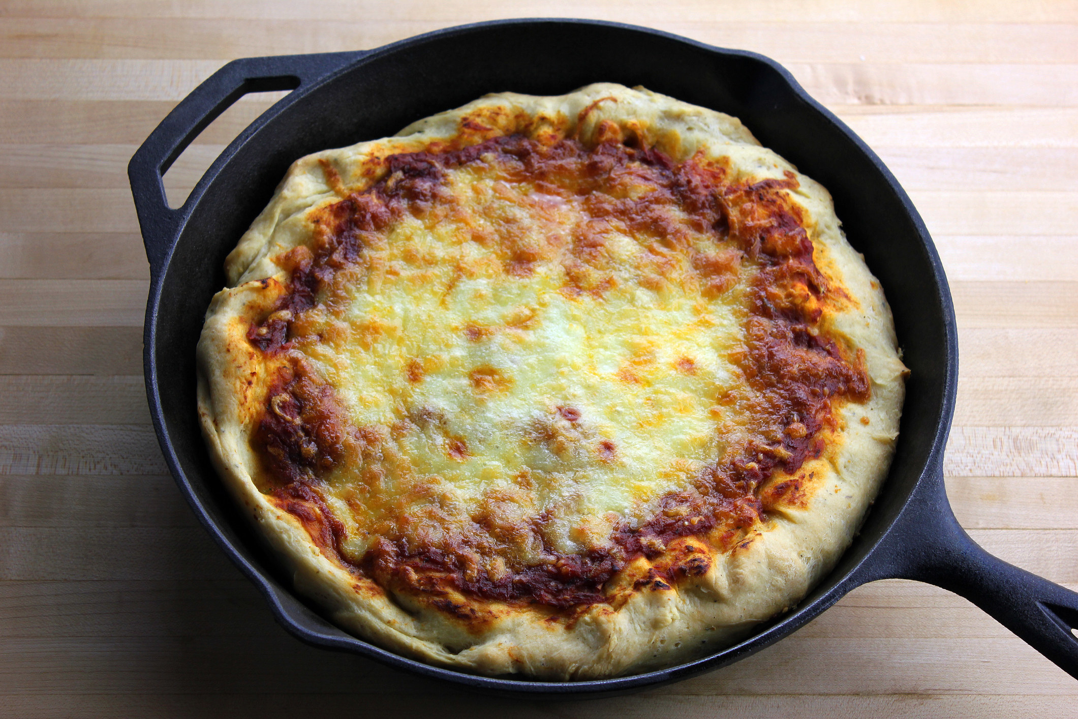 A homemade deep dish pizza in a cast iron pan.