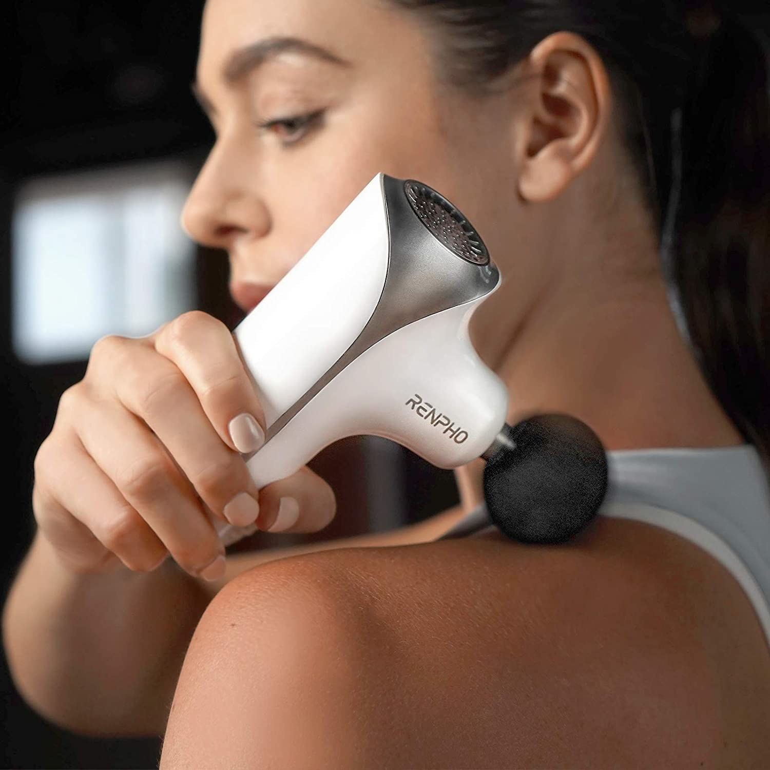 a person using the massage gun on their shoulder