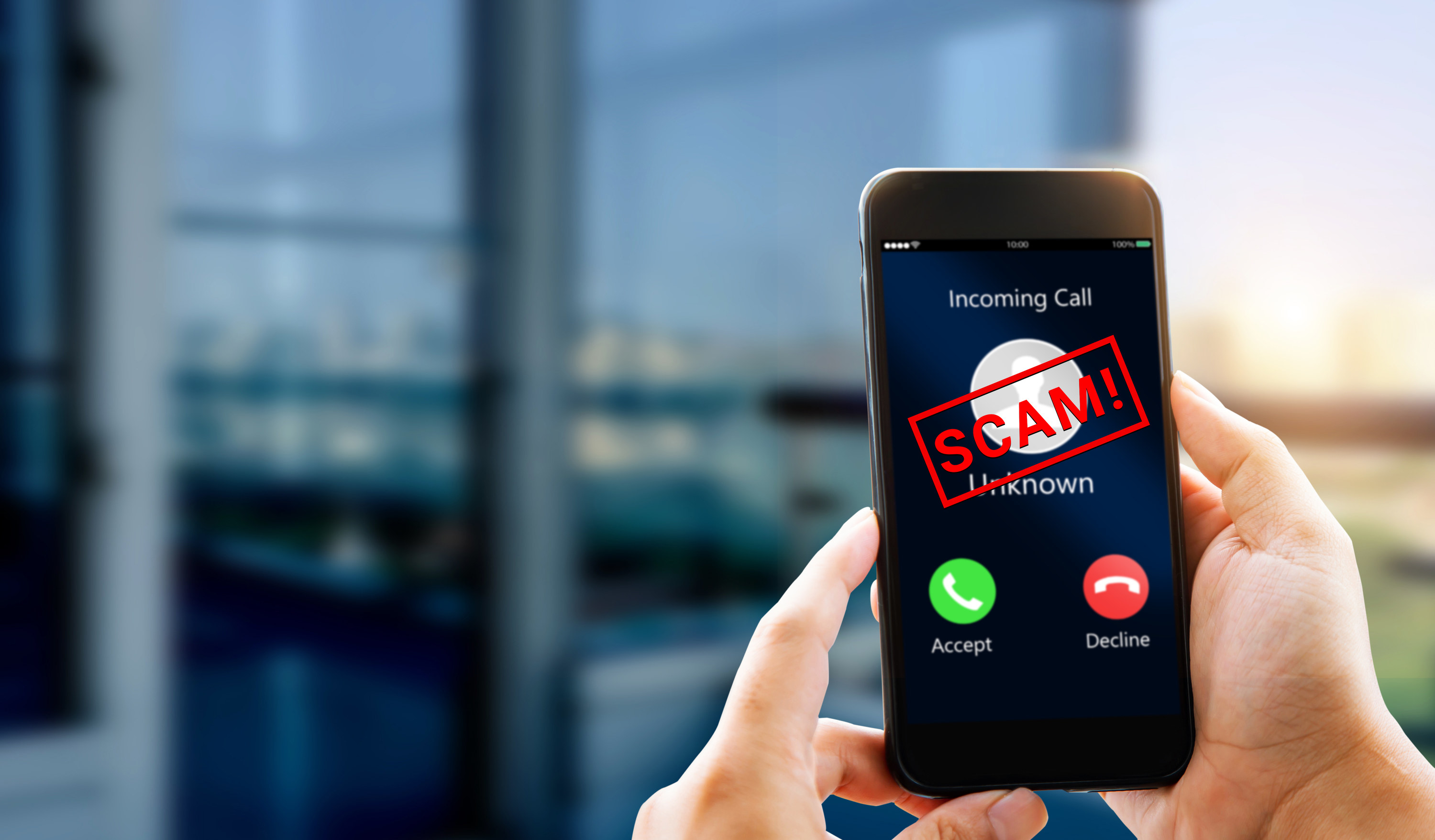 person holding a smartphone with an incoming call marked scam