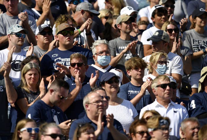 Two Penn State fans are wearing masks and surrounded by fans not wearing masks in the stands during the Ball State Cardinals versus Penn State Nittany Lions game on September 11, 2021 at Beaver Stadium in University Park, PA.