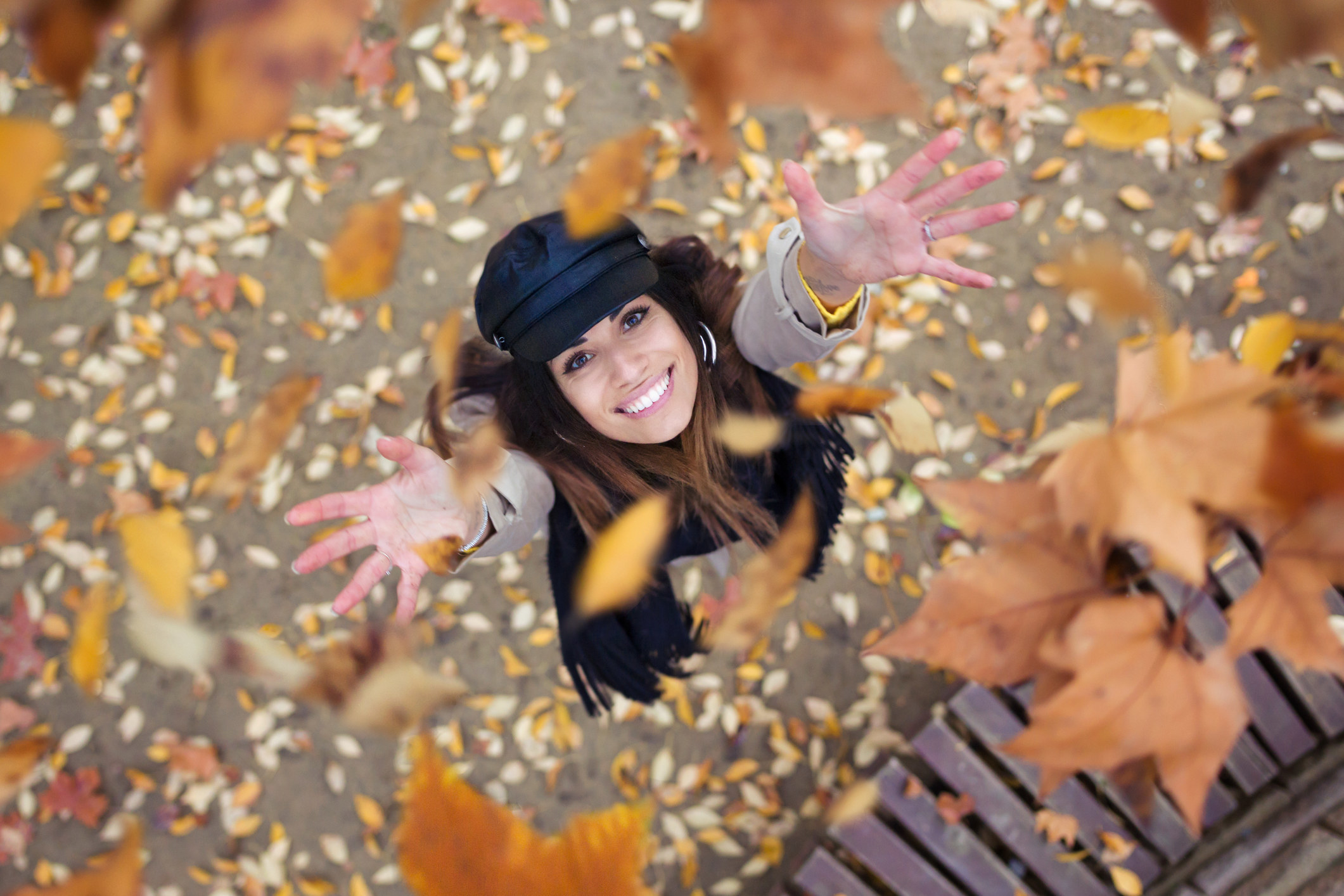 A woman throwing fall leaves into the air