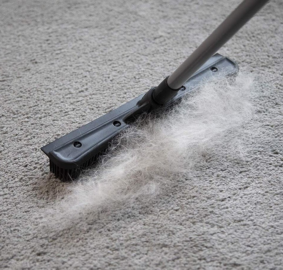 The broom collecting fur off a carpet