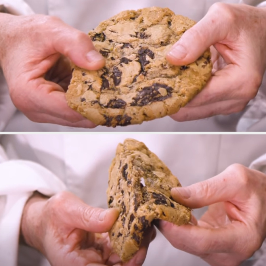 baker holding a large cookie and snapping it in half