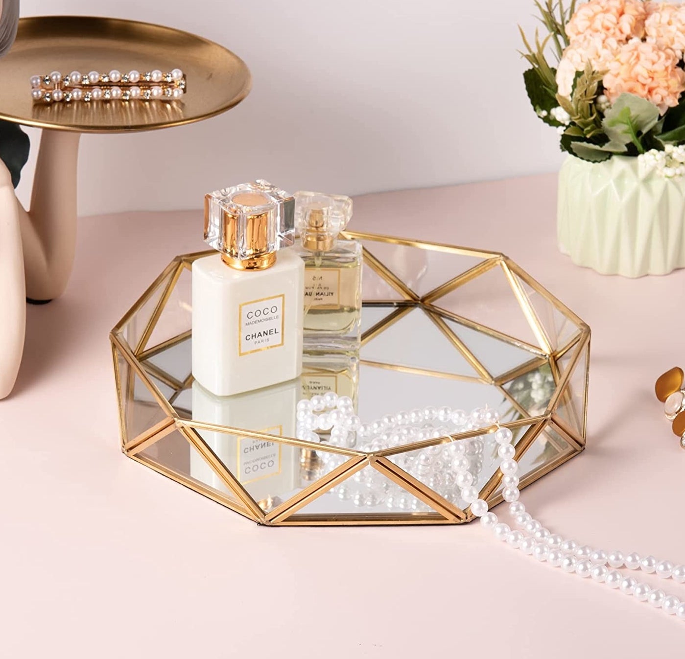 the tray on a table with perfume and pearls in it
