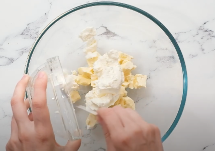 Someone putting ingredients in a mixing bowl