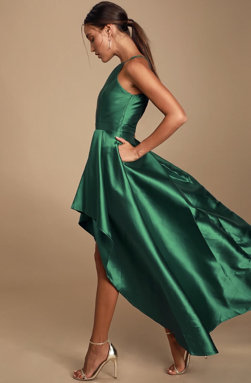 Model from side strutting in the green dress with shiny gold heels