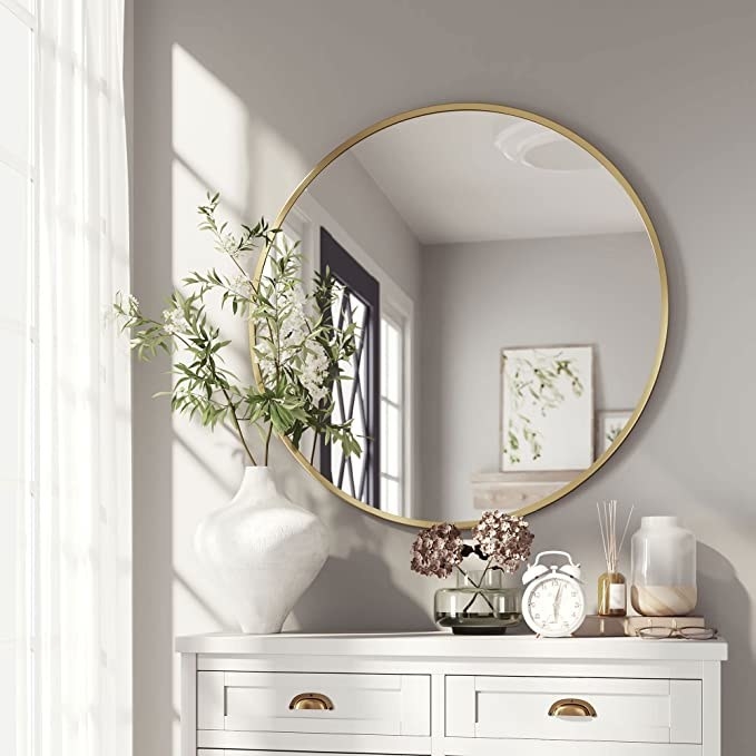 the round mirror over a dresser in a bedroom