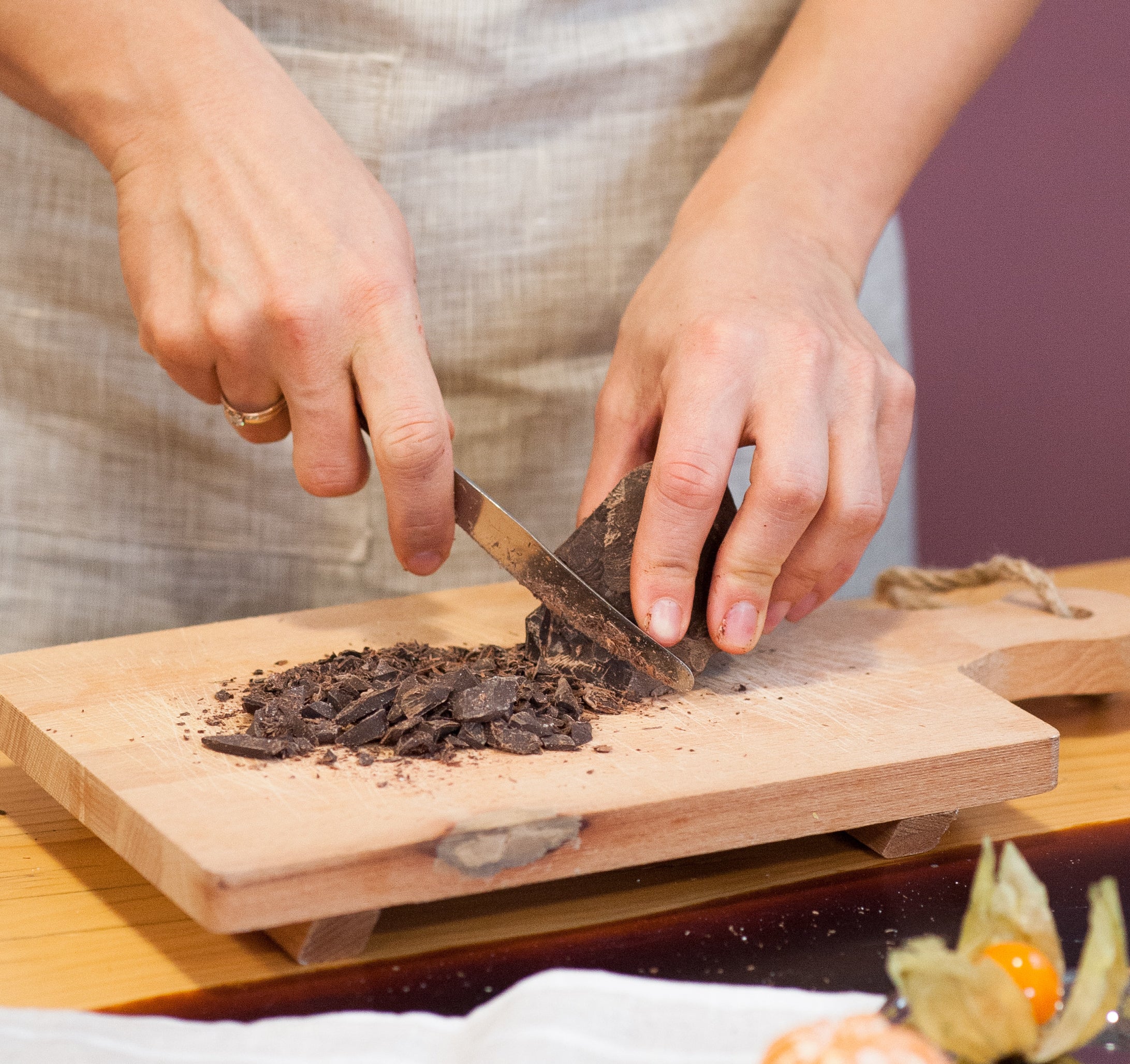 chopping chocolate into fine pieces on a wooden cutting board