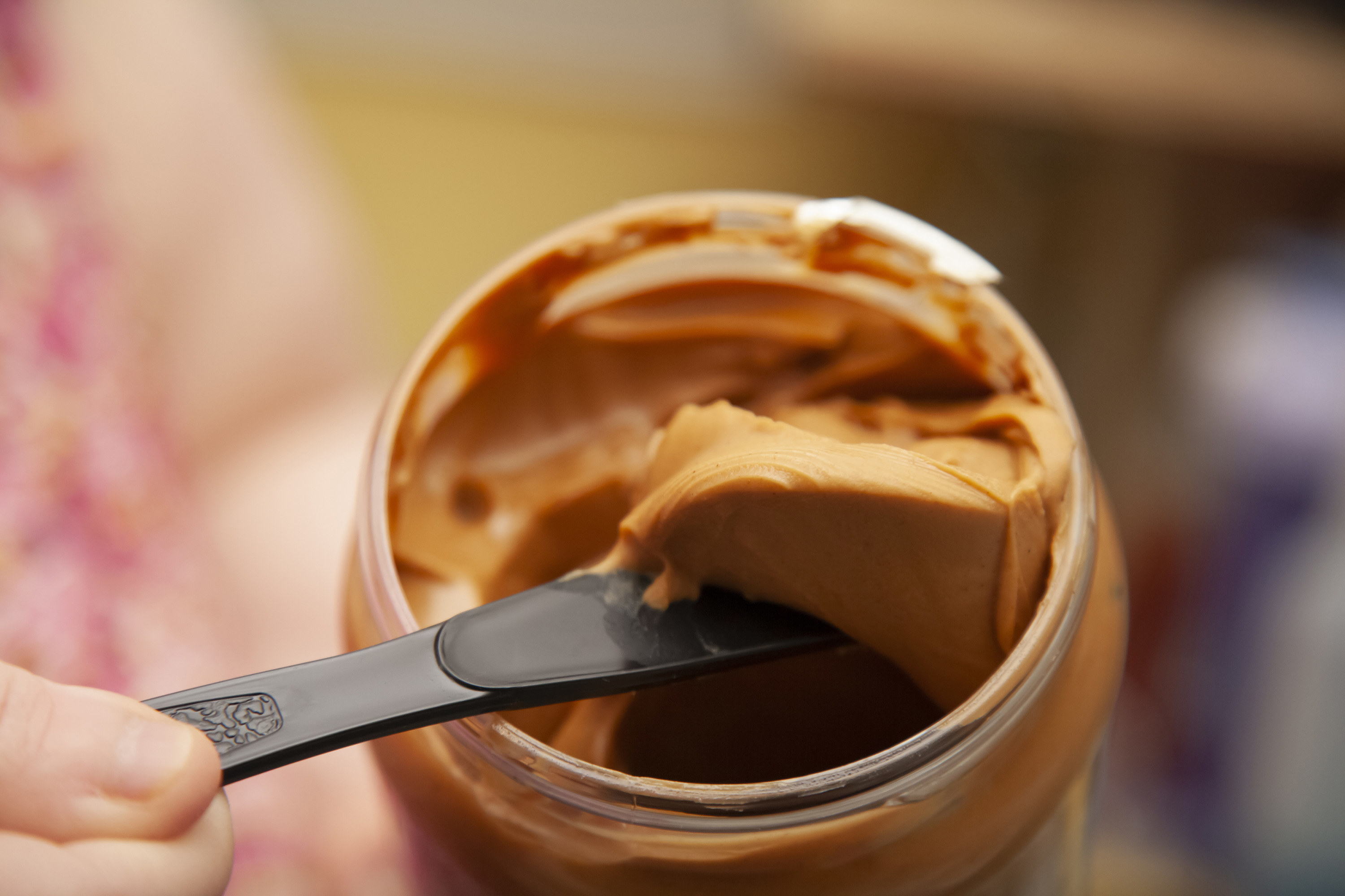 scooping peanut butter out of a jar with a knife