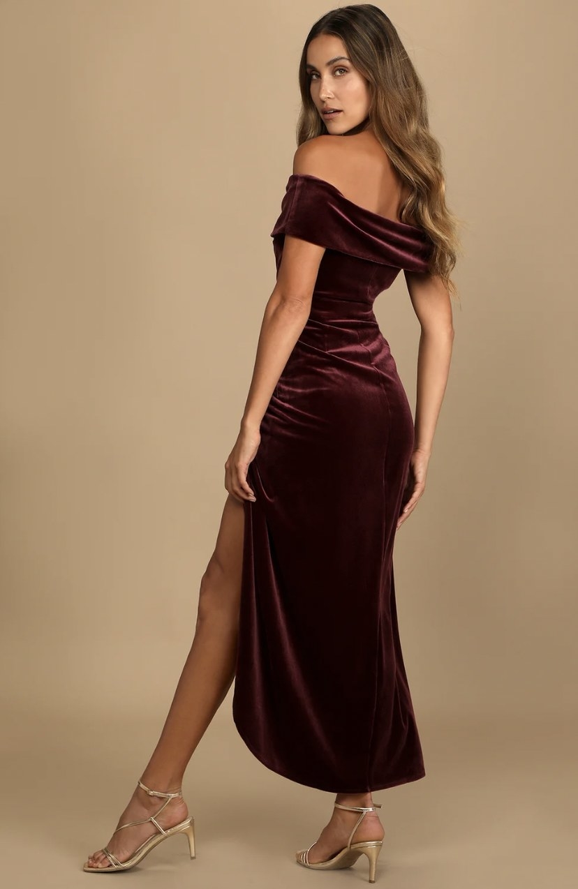 Model from side pointing toe in the burgundy dress