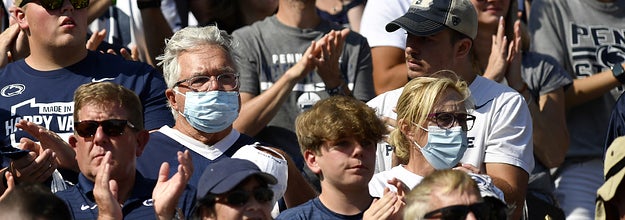 Two Penn State fans are wearing masks and surrounded by fans not wearing masks in the stands during the Ball State Cardinals versus Penn State Nittany Lions game on September 11, 2021 at Beaver Stadium in University Park, PA.