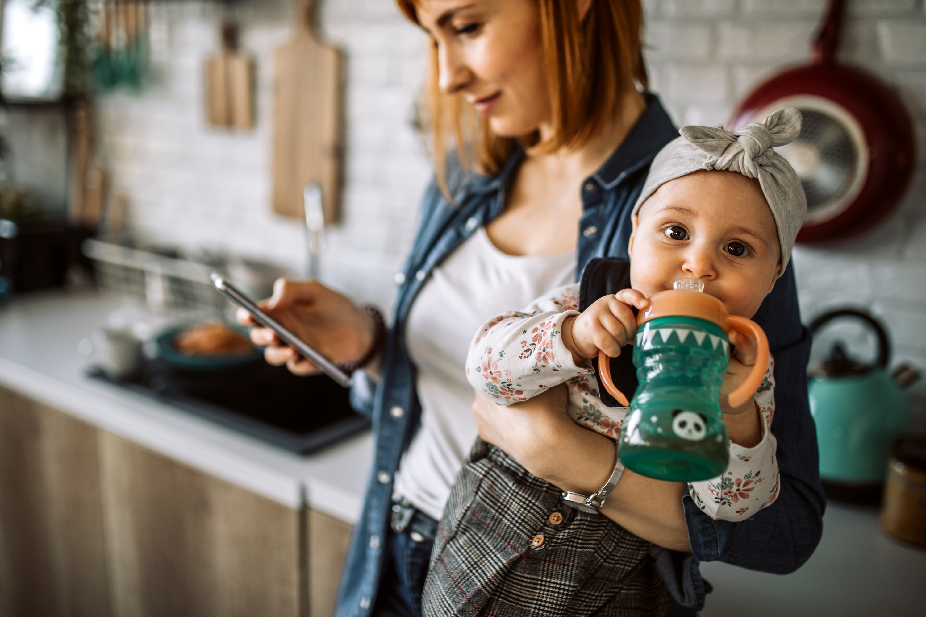 single mom dialing a phone call while holding her baby