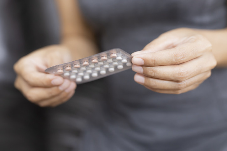 A woman holding a pack of birth control pills