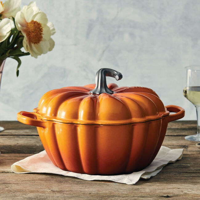 A dutch oven in the shape and color of a pumpkin is shown